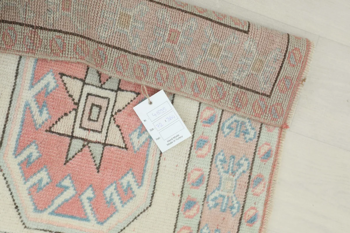 Detail of the rug with a product tag, showing the texture and colors of the vintage wool.
