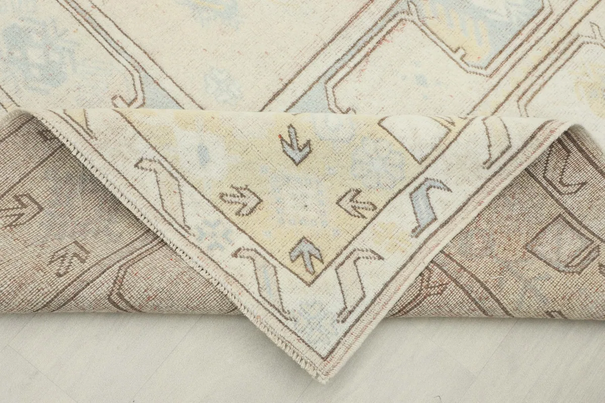 Corner of the rug folded back, revealing the wool pile and cotton foundation from the underside.