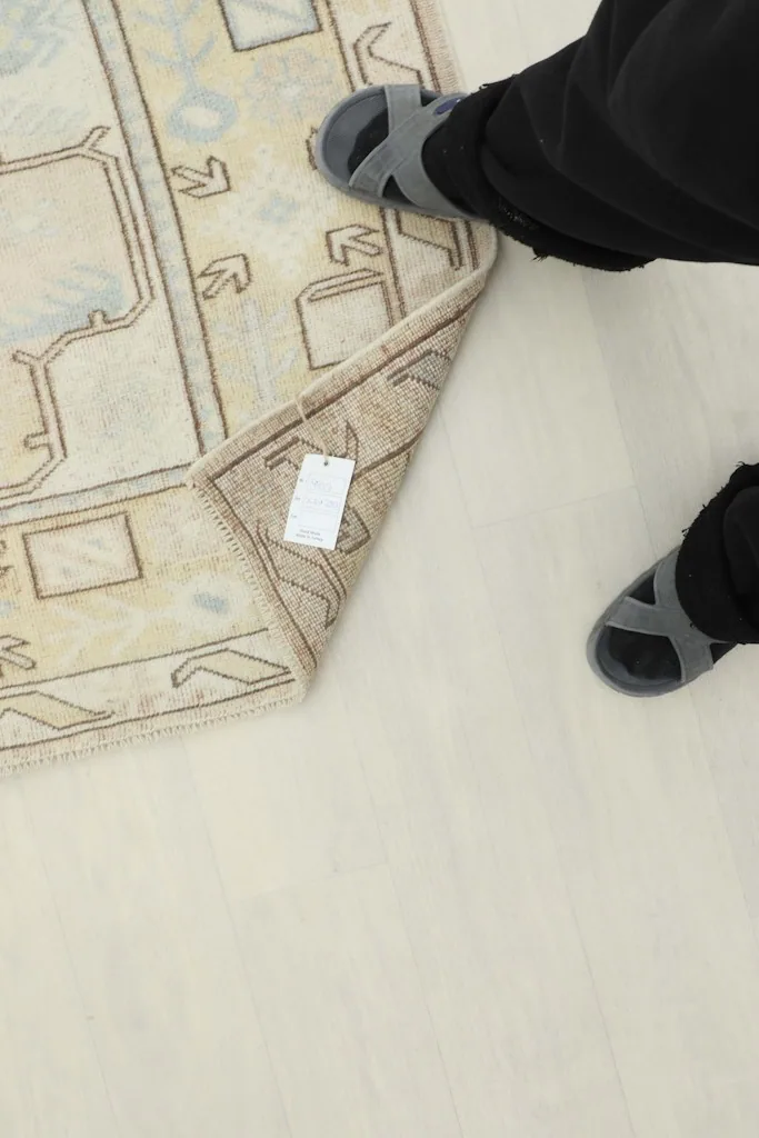 Person's feet next to the rug, with a price tag visible on the underside, demonstrating the rug's size.