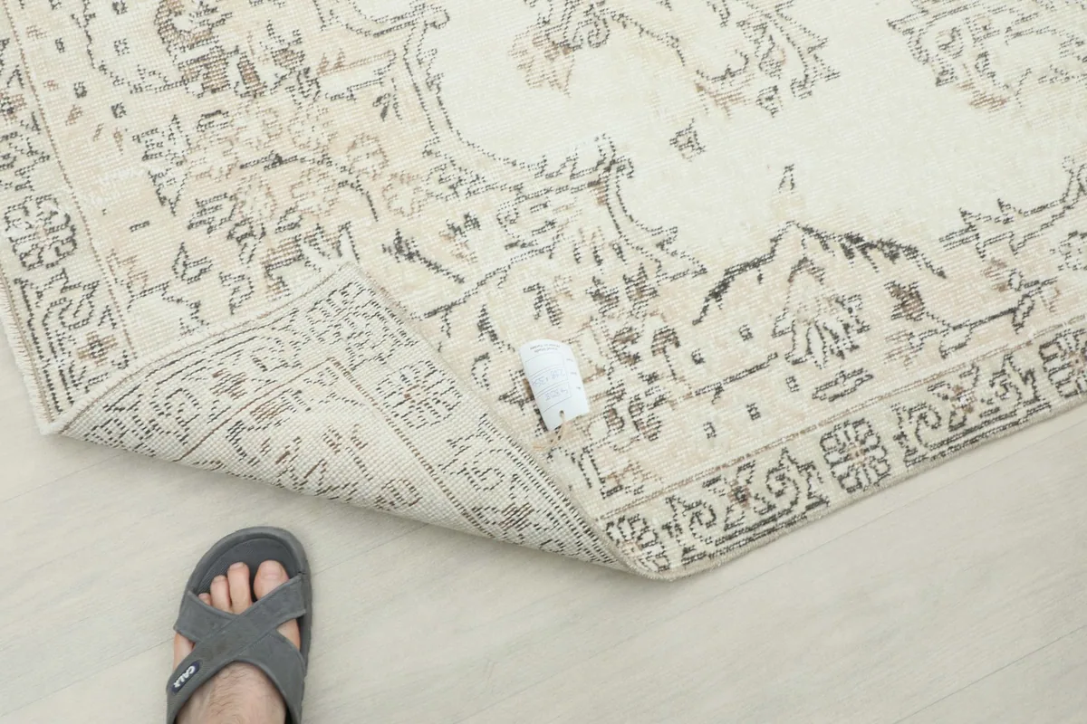 A foot on the rug's corner, demonstrating the low pile and vintage appearance