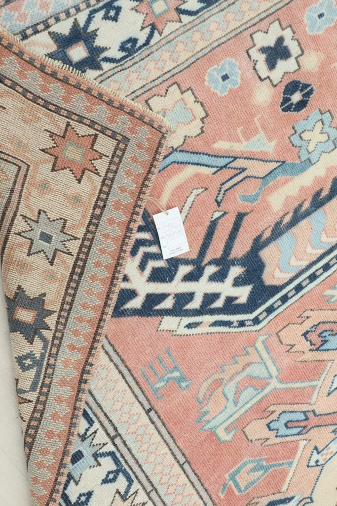 View of the back of the rug, showing the hand-knotted construction and cotton foundation with a tag.