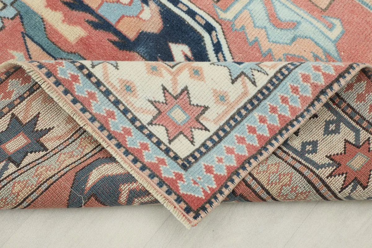 Corner of the rug folded back, showcasing the detailed border patterns and the rug's flexibility.