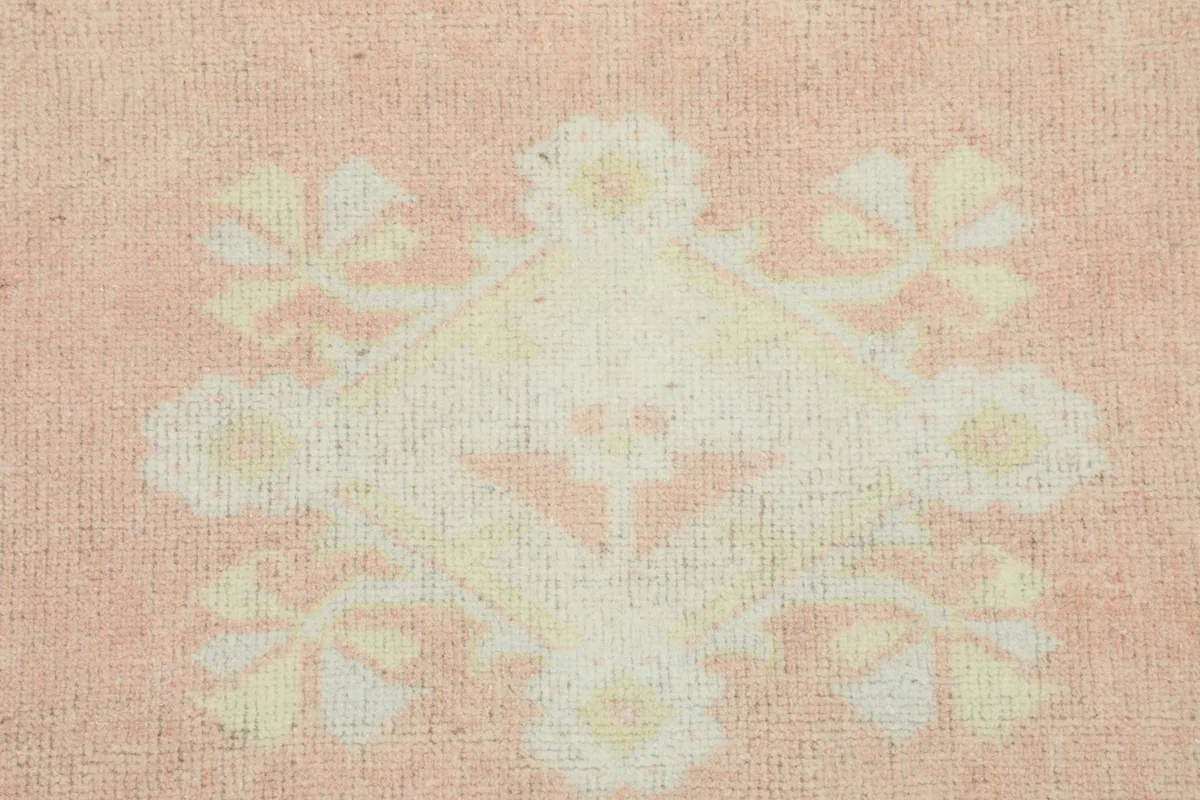 Extreme close-up of a single floral motif on the rose field, showing texture and faded colors