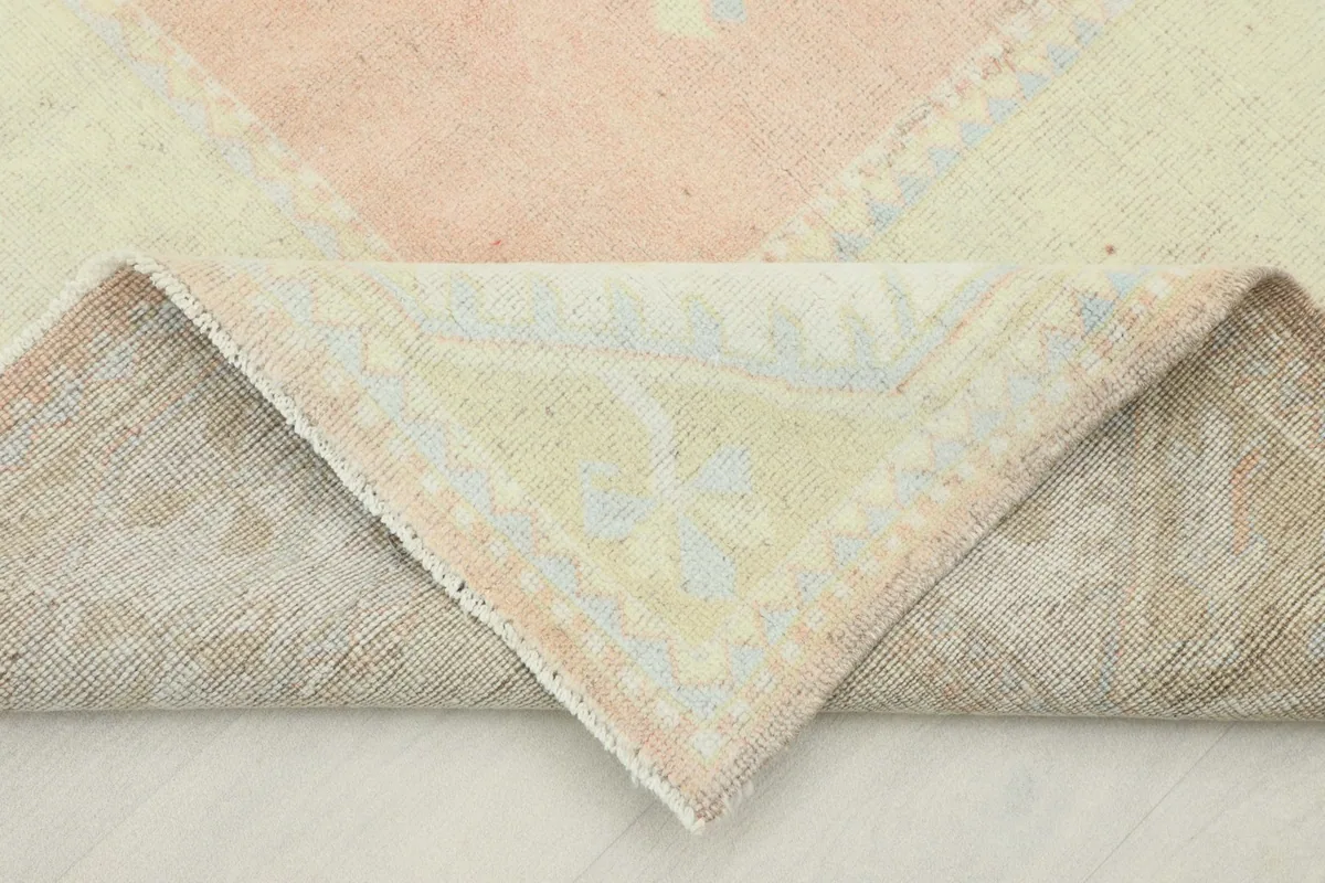 Corner of the rug folded back to show the wool pile on cotton foundation and weaving