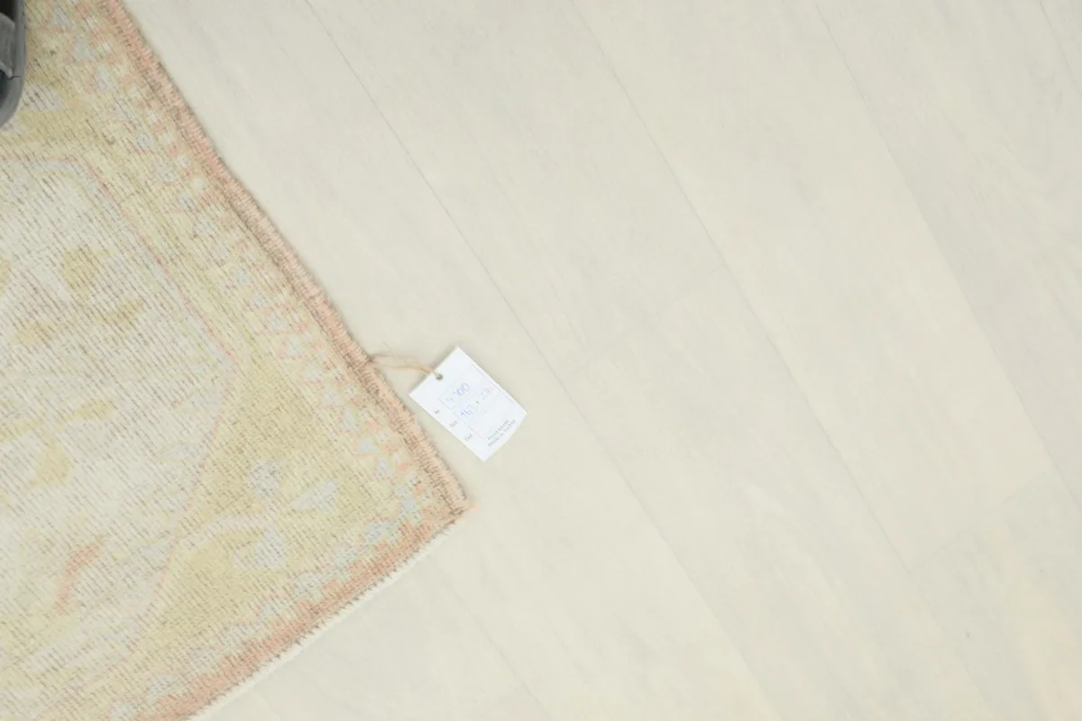 Overhead view of the rug's corner with the product tag on a light wooden floor