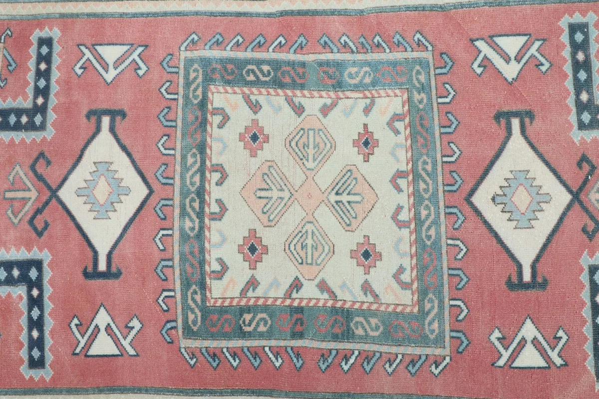 Overhead detail of the central beige medallion with small geometric motifs on the rose field.