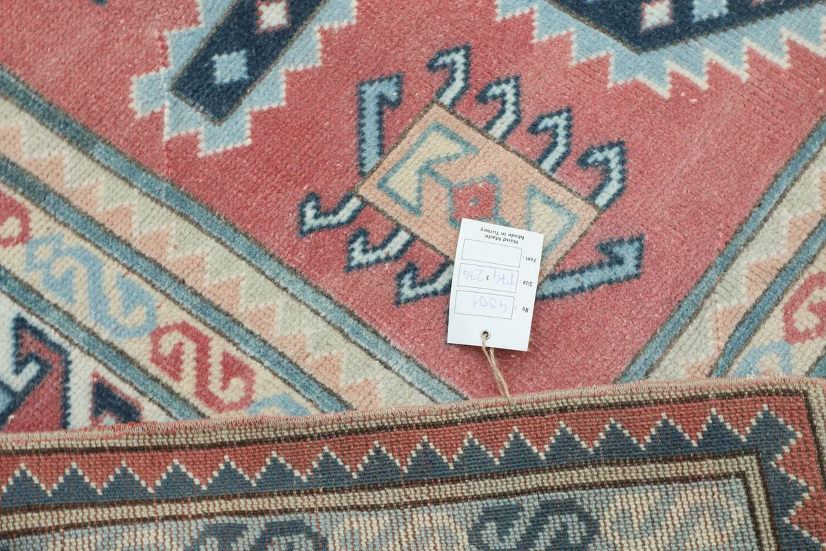 View of the rug's back and a detail of the hand-knotted construction with a product tag.