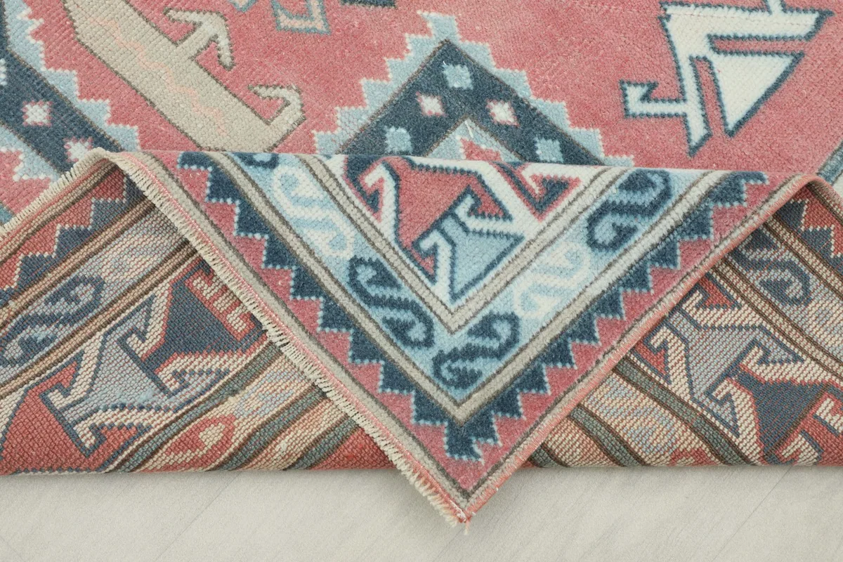 Folded corner of the vintage rug, showing the back and the density of the hand-knotted wool pile.