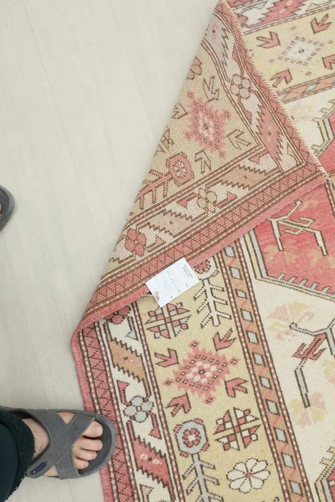 Underside of the vintage rug with a partial fold, showing the hand-knotted cotton foundation.