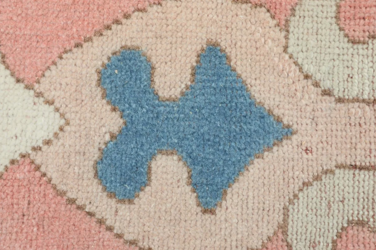 Detailed close-up of the hand-knotted wool pile, showing the blue and rose colors.