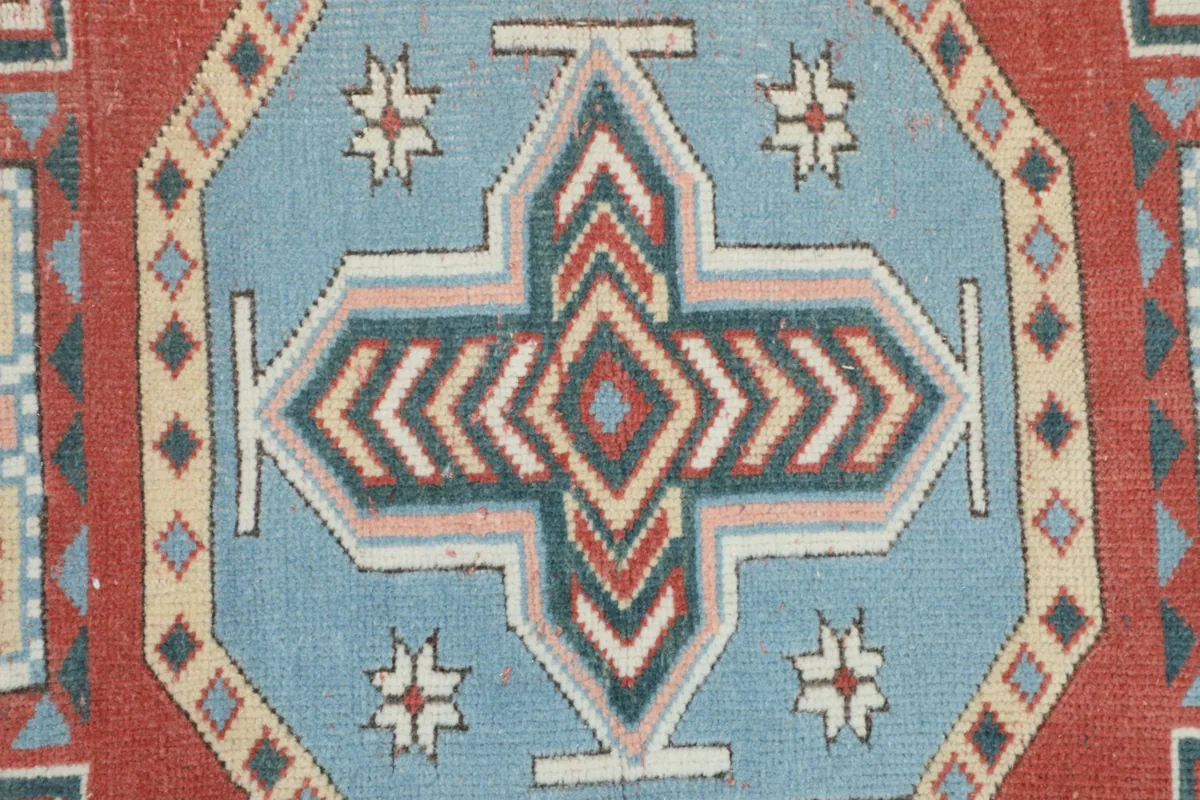 Close-up of the central blue and red cross-like motif within the medallion