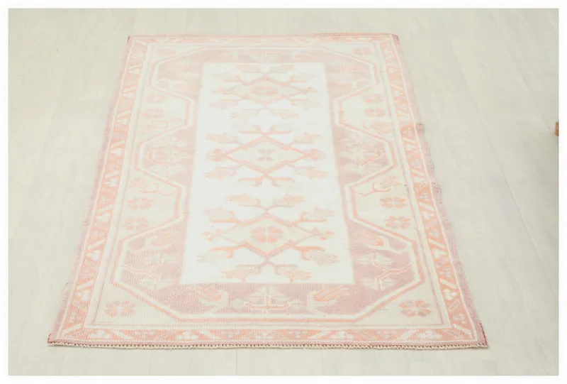 Full top view of the 2'9" x 4'4" rose and ivory vintage Anatolian area rug on a white background.