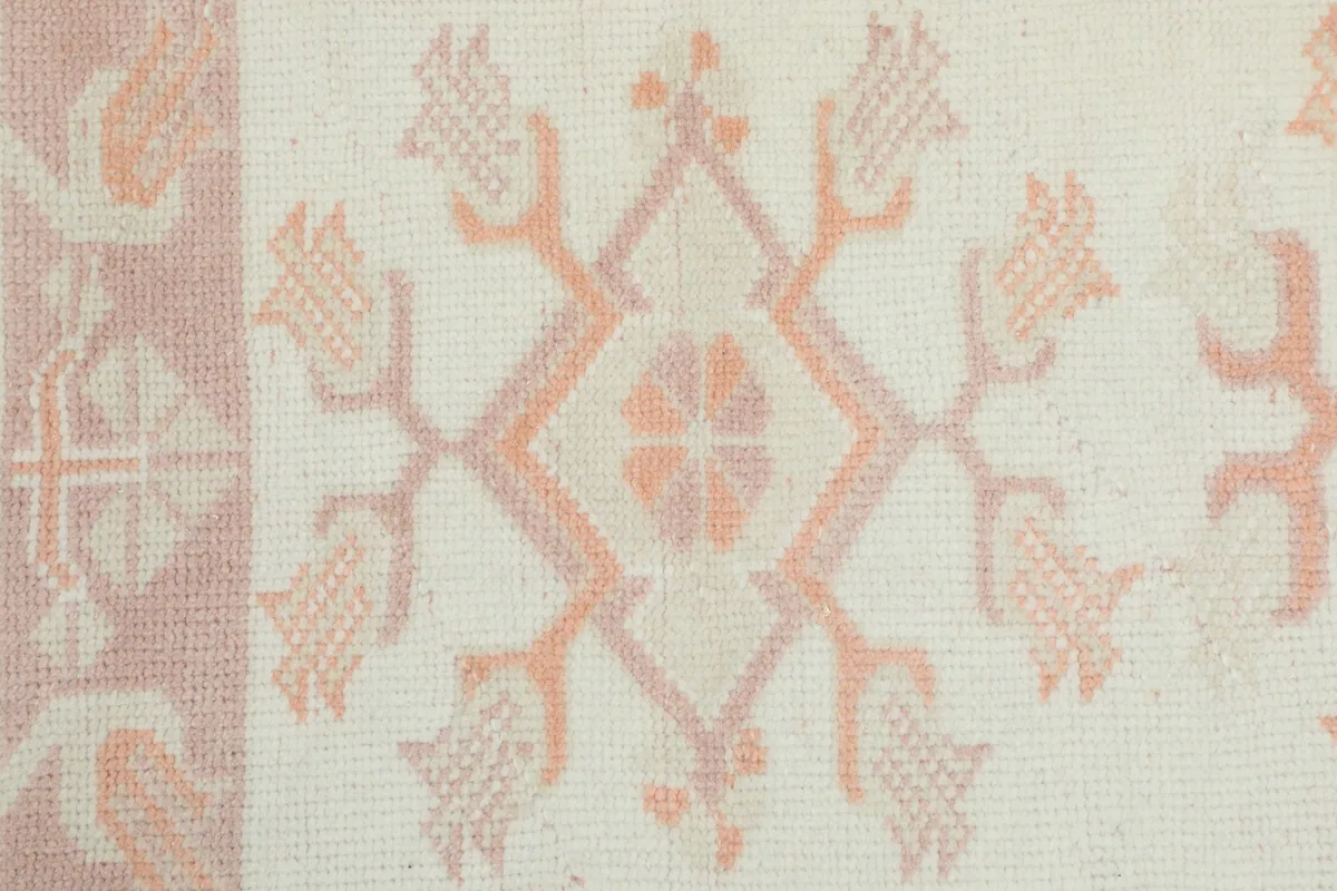 Detailed view of the hand-knotted geometric patterns and color variations in the rug's pile.