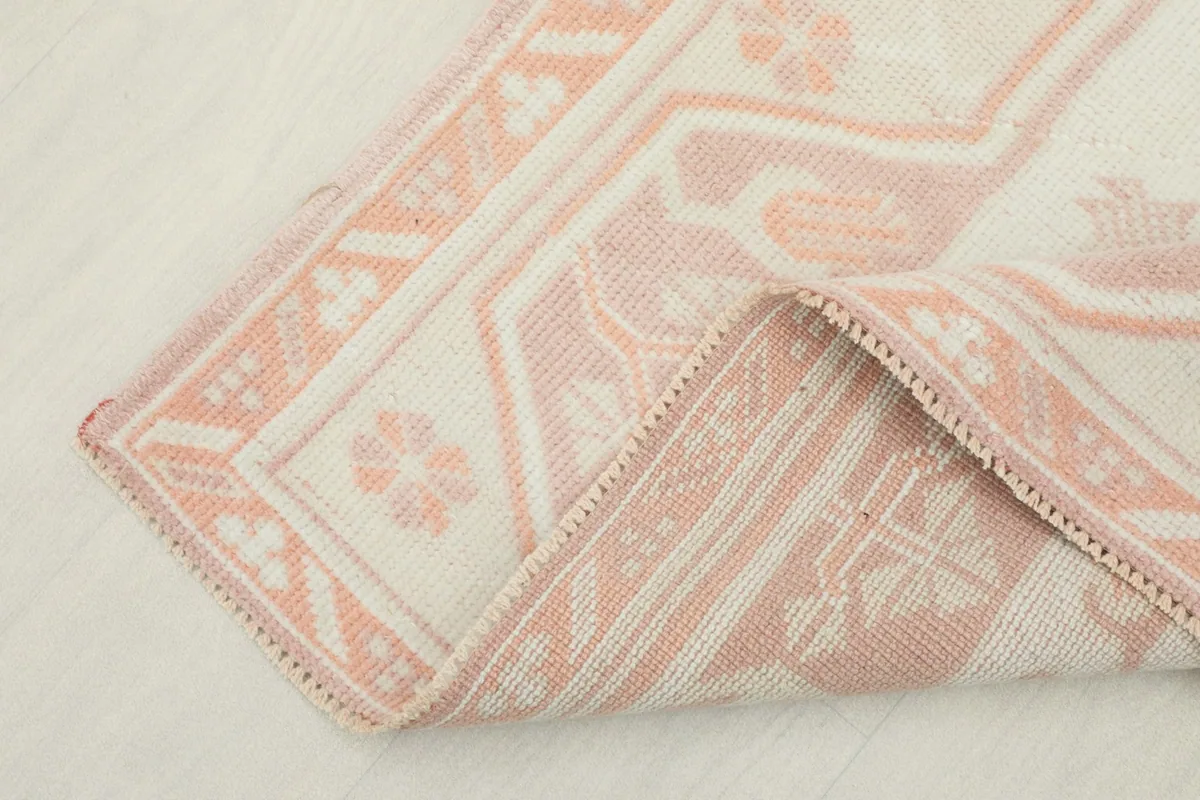 Corner of the rug folded to show the hand-knotted construction and cotton foundation from the reverse side.
