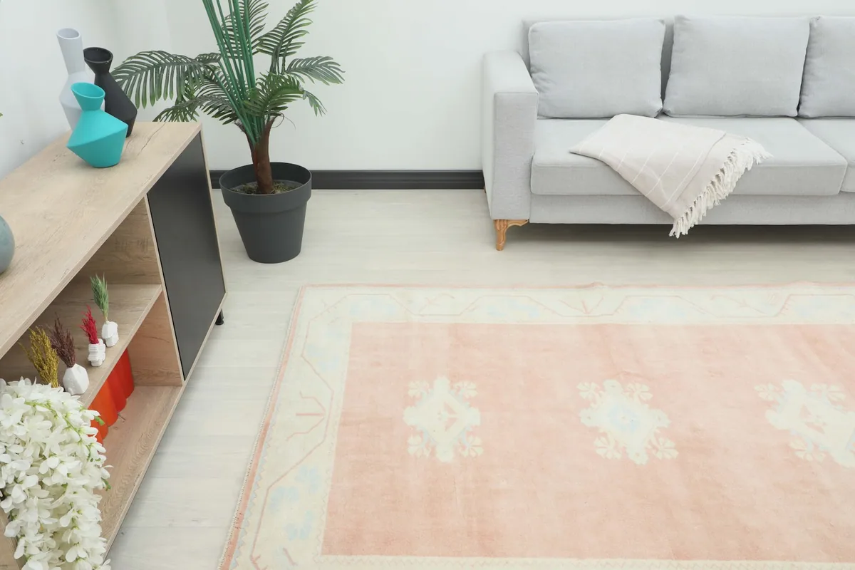 Angled view of the rug in a room, highlighting the rose and ivory colors and overall placement