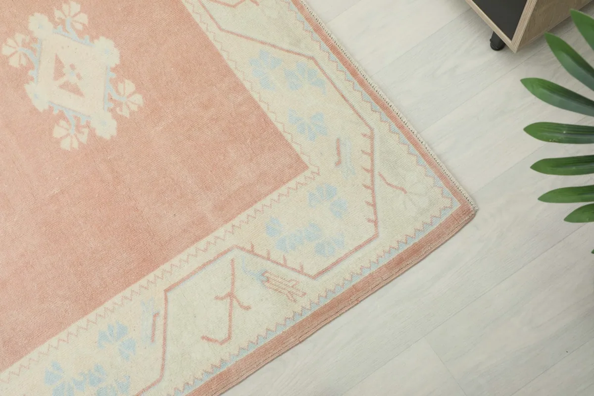 Corner detail of the rug's ivory border, showing geometric patterns and color variations