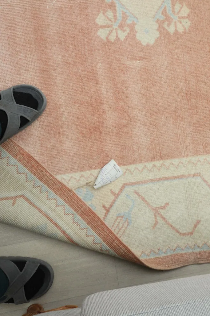 Close-up of the rug's side, showing the finished edge and a small tag, with slippers nearby