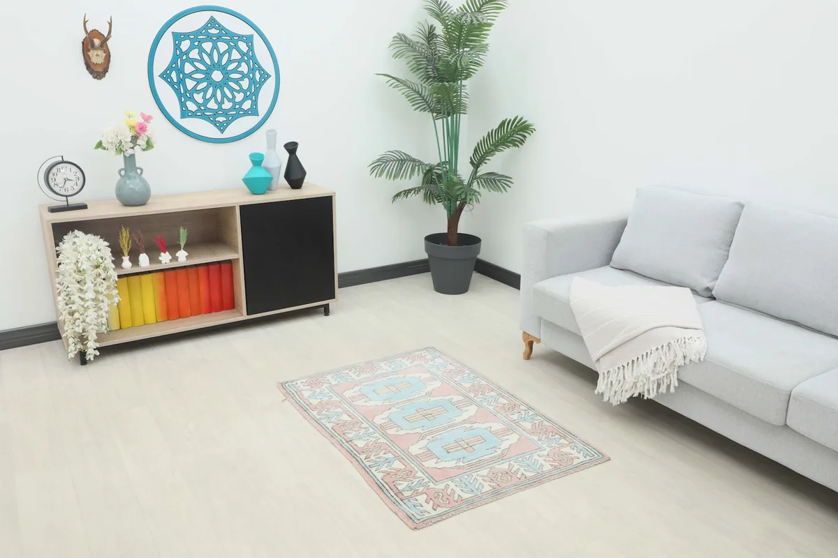 Vintage pink and blue geometric rug placed in a modern living room setting with a gray sofa.