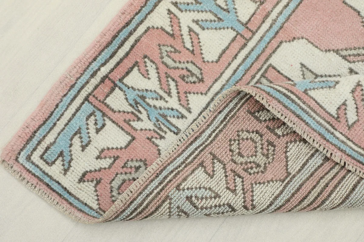 Corner of the rug folded back, revealing the backside and construction of the hand-knotted wool pile.