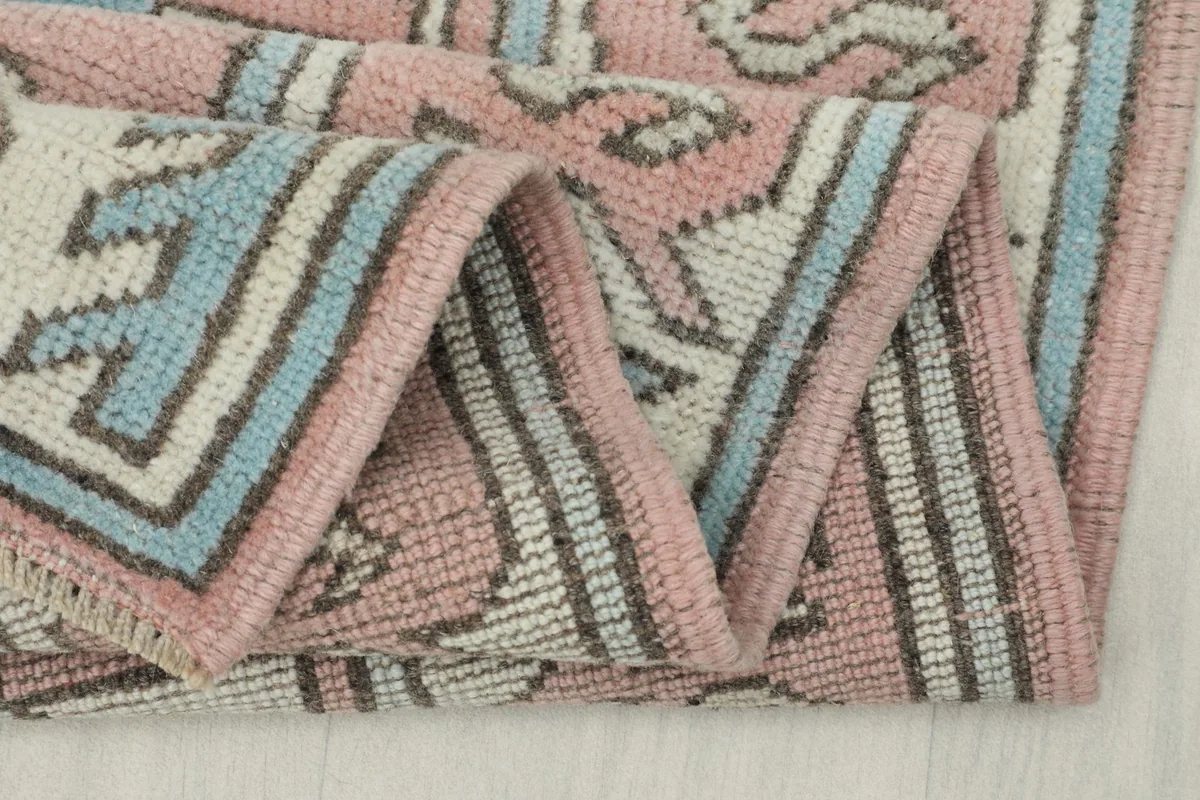 Close-up of the rug's edge and fold, showing the tightly woven cotton foundation and wool pile.