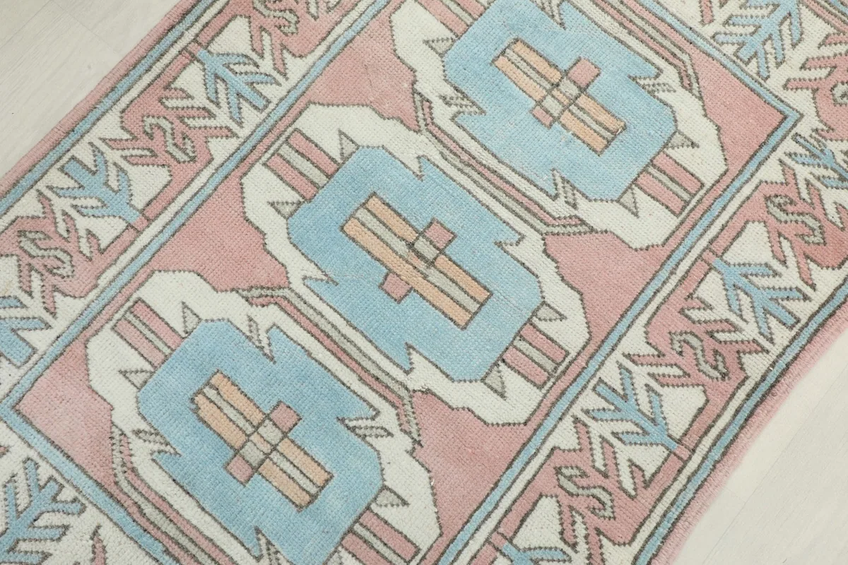 Overhead diagonal view focusing on the central blue geometric motifs against the pink field.