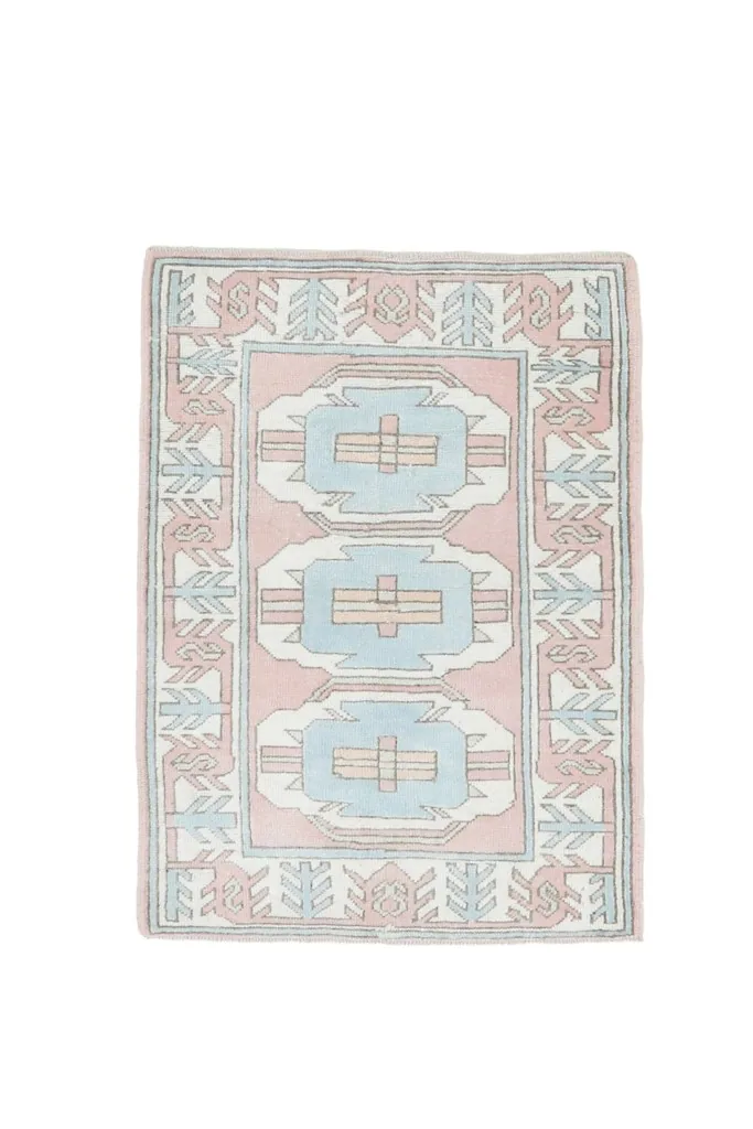 Full overhead view of the vintage pink and blue geometric Anatolian rug on a white background, slightly cropped.