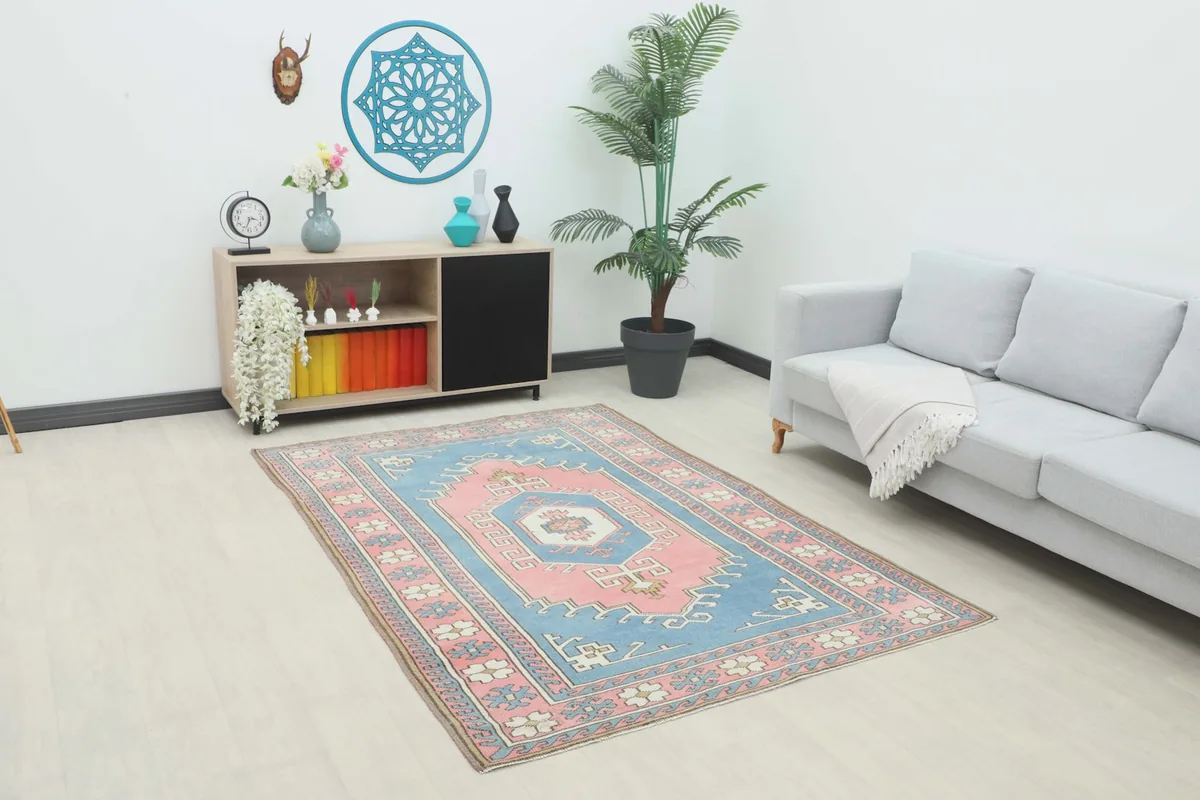 Vintage blue and pink area rug displayed in a bright room with light furniture.