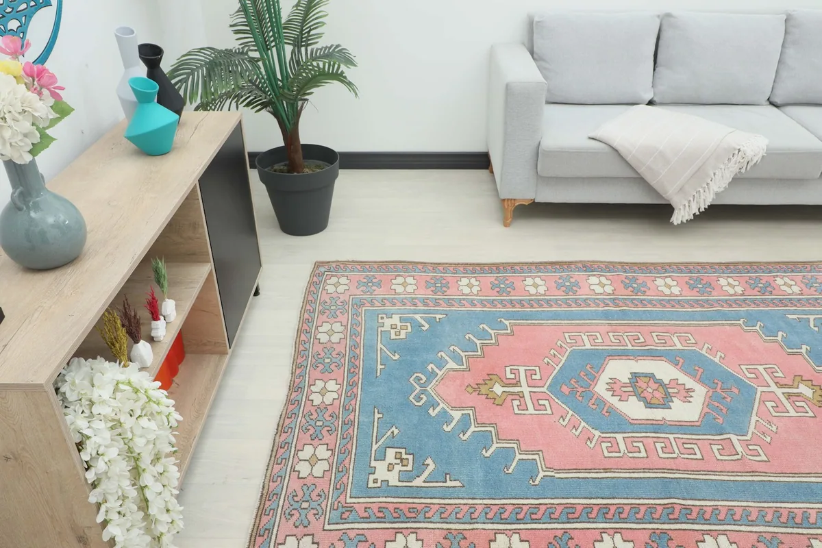 Angle view of the blue and pink vintage rug in a living space with a sofa and cabinet.
