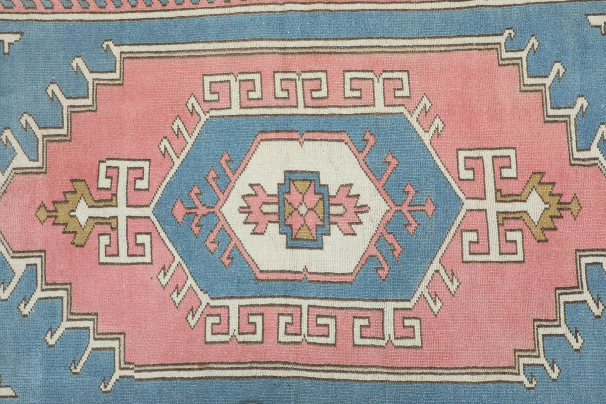 Close-up of the central geometric medallion featuring blue, pink, and ivory colors.