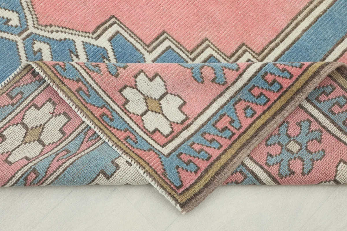 Folded corner of the rug, showcasing the hand-knotted wool pile and border patterns.