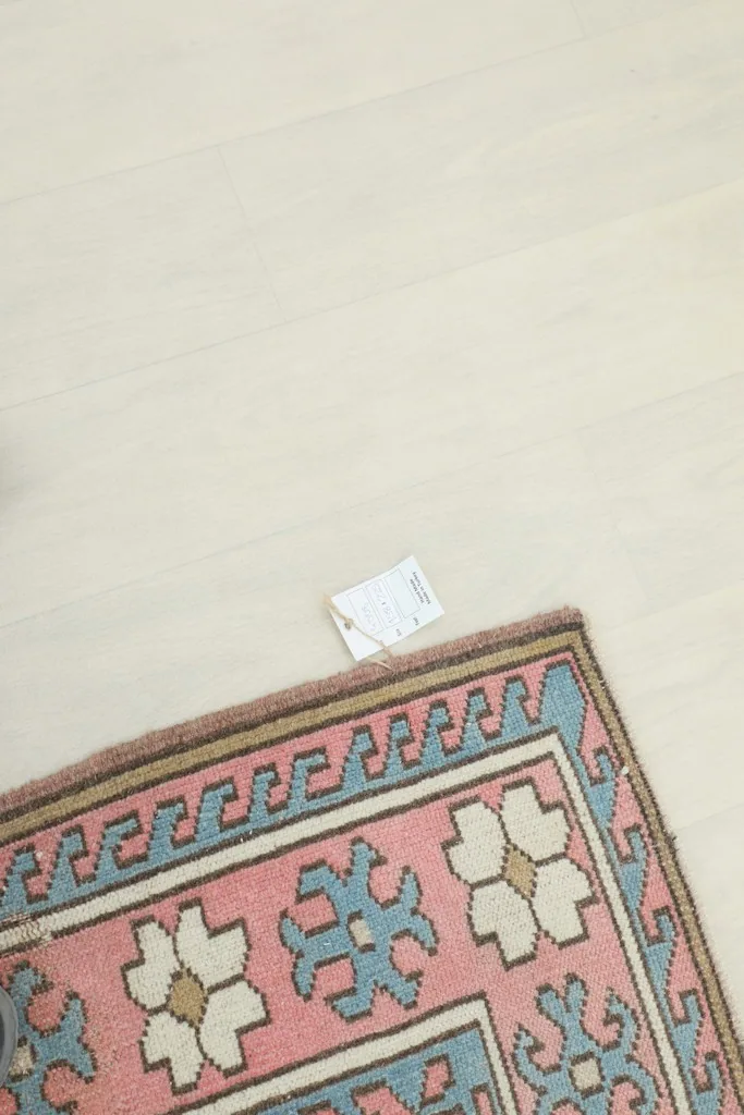 Close-up of the rug's edge, showing the pile and a small tag on the light floor.