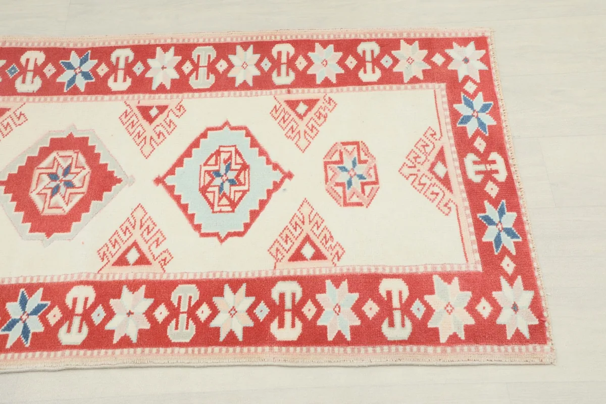 Close-up of the geometric patterns and red border at one end of the rug