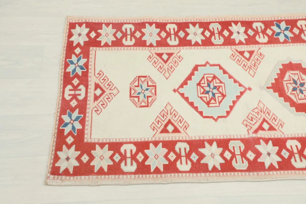 Detailed view of the rug's patterns and border, showing ivory, red, and blue colors