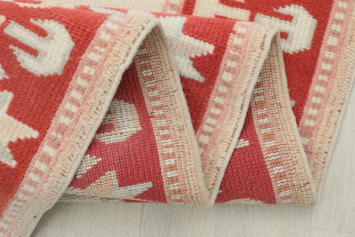 Close-up of the rug's folded edge, revealing the low wool pile and hand-knotted construction