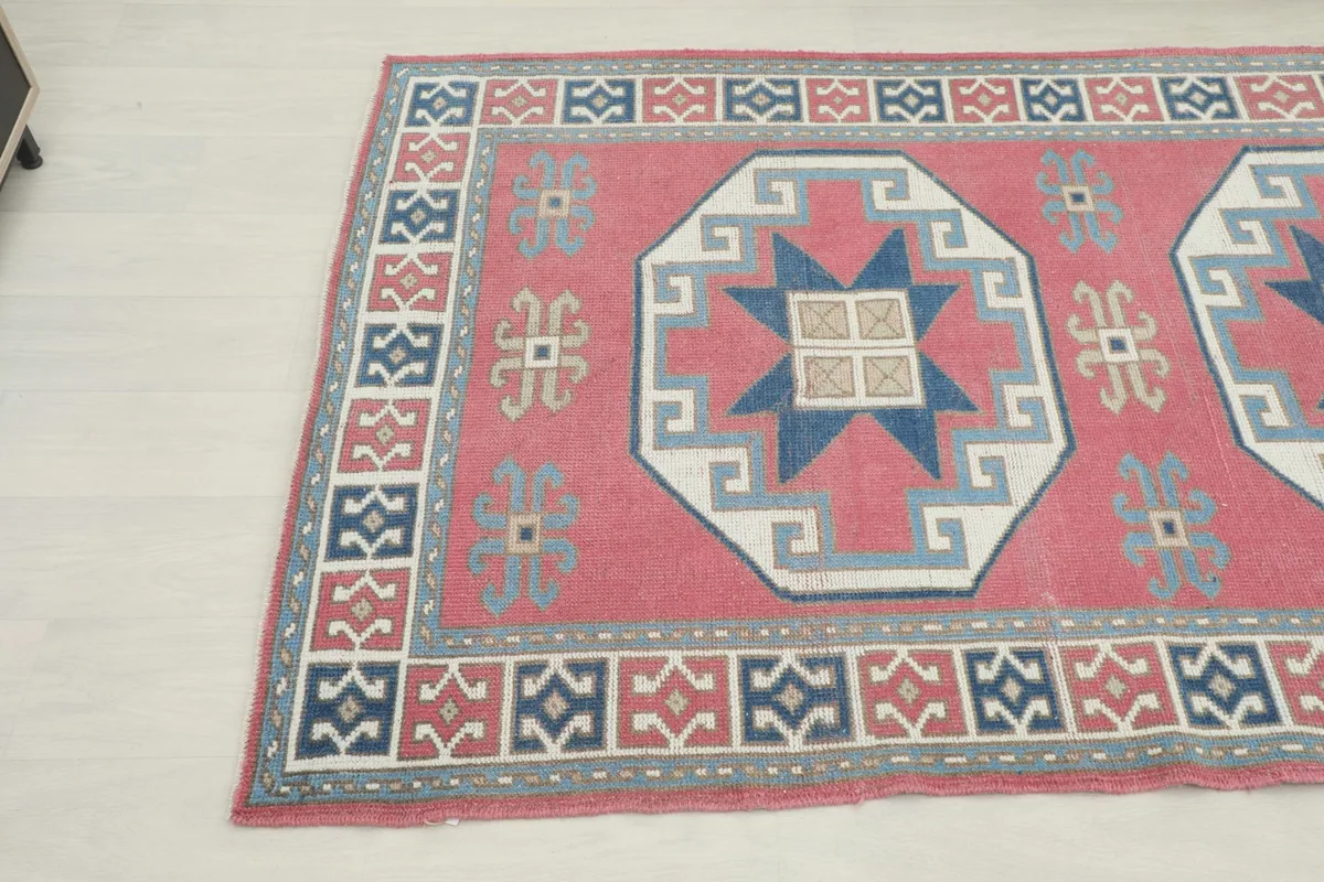 Overhead angle view capturing the rug's geometric design and color palette of rose, navy, and gray