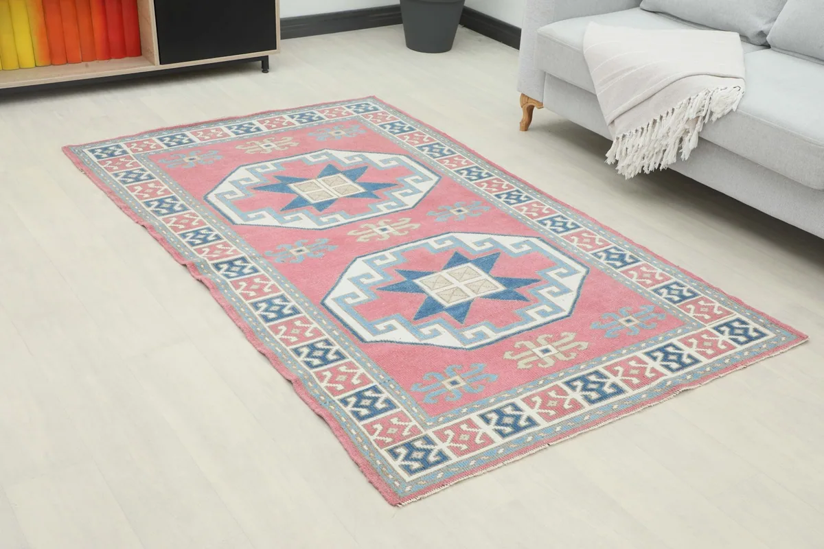 Angle view of the rose and navy geometric rug in a living room with a gray sofa