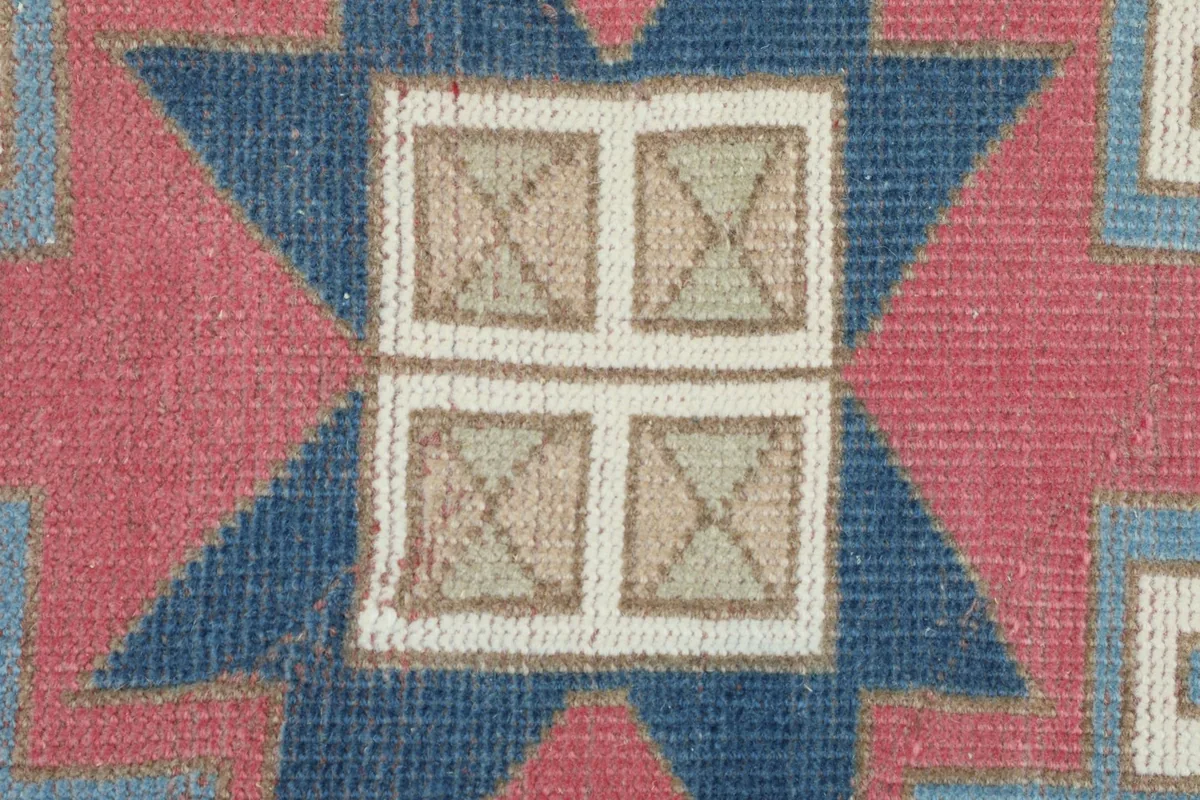 Extreme close-up detail of the central starburst motif with navy, rose, and tan colors