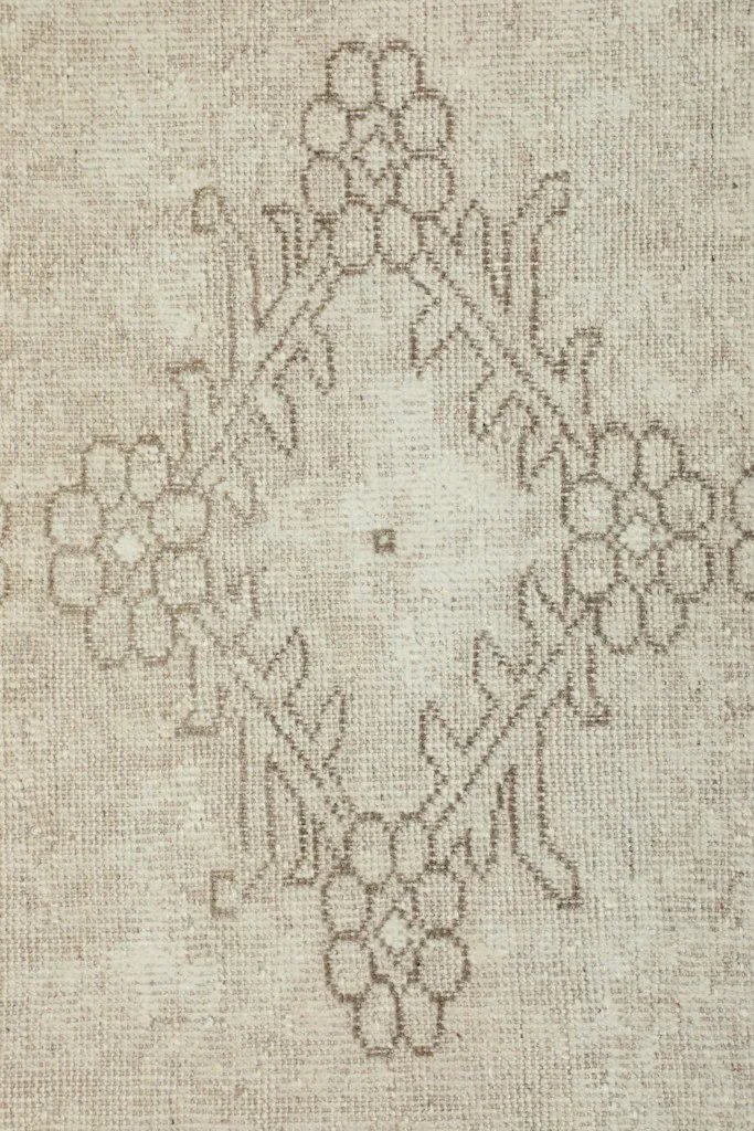 Close-up of a single floral diamond motif with brown outline on the cream rug