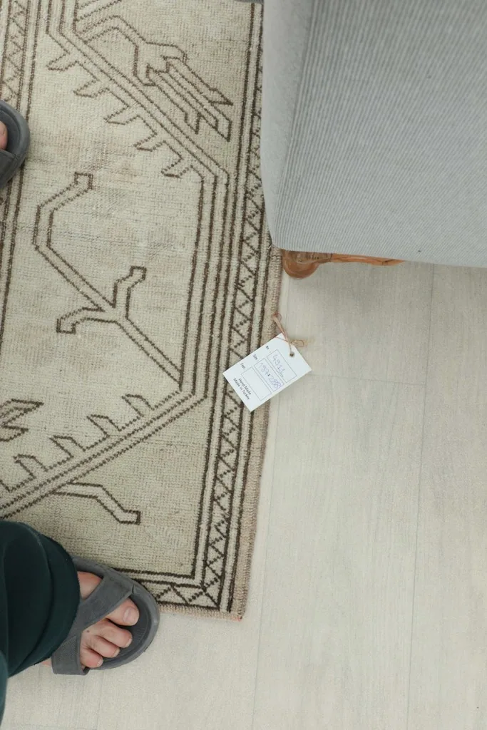 Overhead view of a person's feet on the rug, next to a product tag