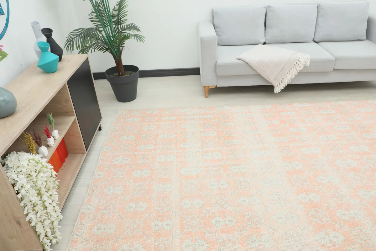 Angle view of the rose vintage rug in a room, showing its scale next to a console and sofa