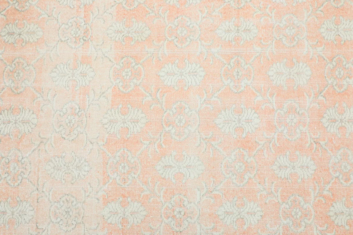 Detailed overhead shot showing the faded ivory geometric motifs on the rose field