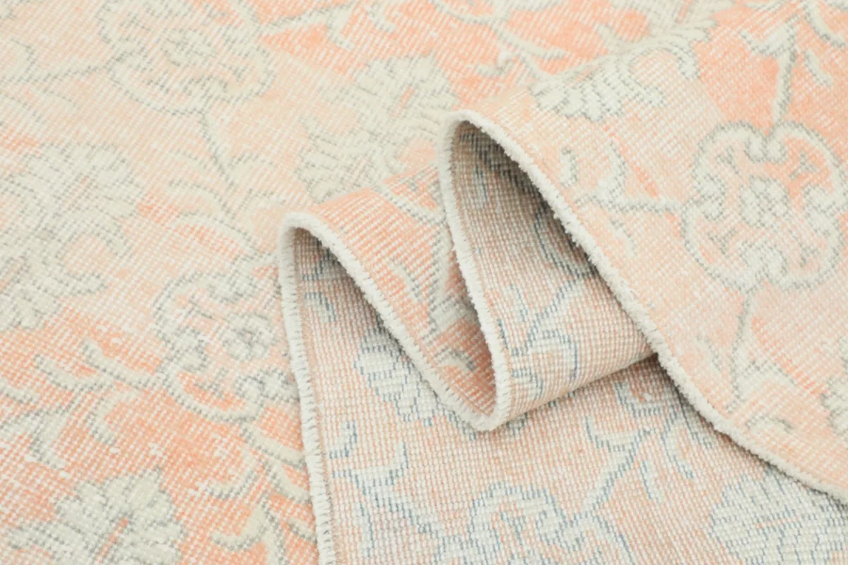 Folded section of the rug, showcasing the texture and faded patterns from a side angle