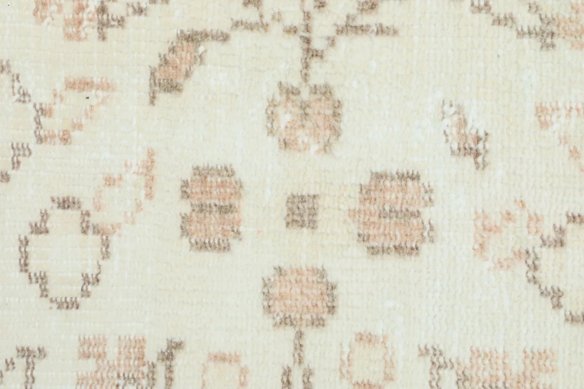 Detailed view of the intricate tan and brown floral motifs against the cream background of the rug pile.