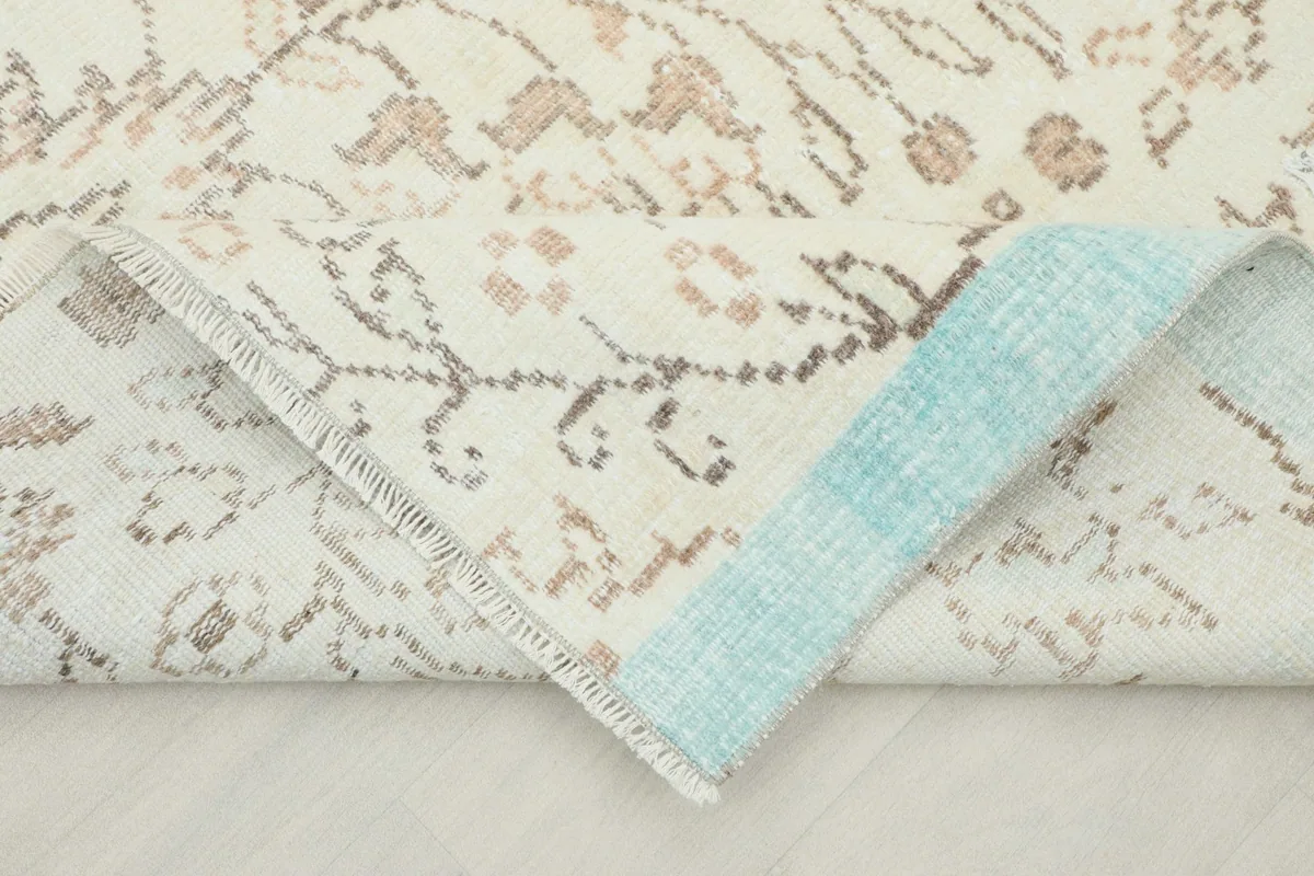 View of a folded corner of the rug, revealing the cotton foundation and the light blue color on the reverse side.