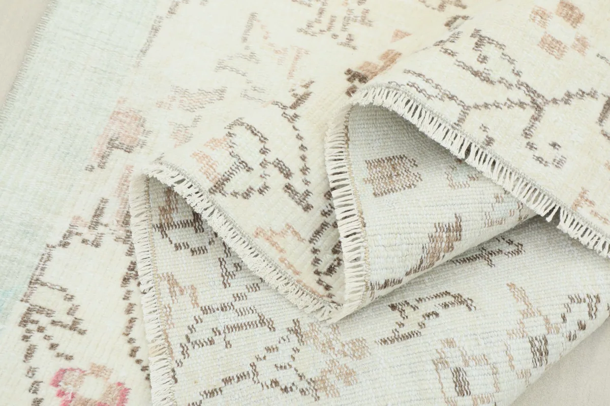 Multiple folds of the rug, showcasing the texture of the wool pile and the hand-knotted construction.