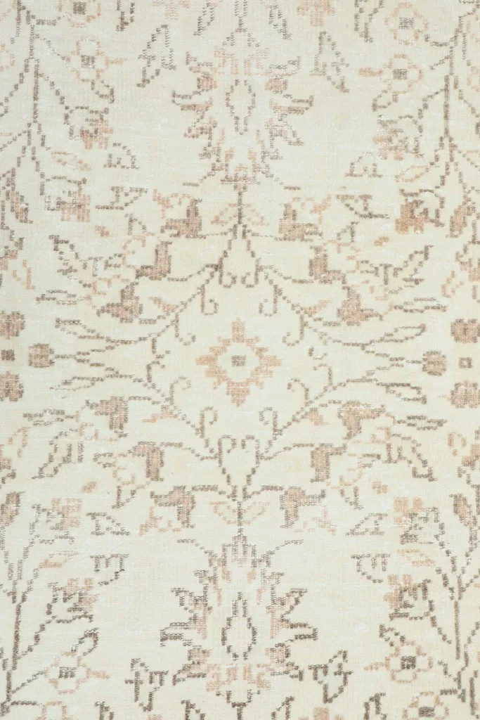 Overhead close-up of the rug's center, highlighting the repeating floral and vine patterns in tan and brown.