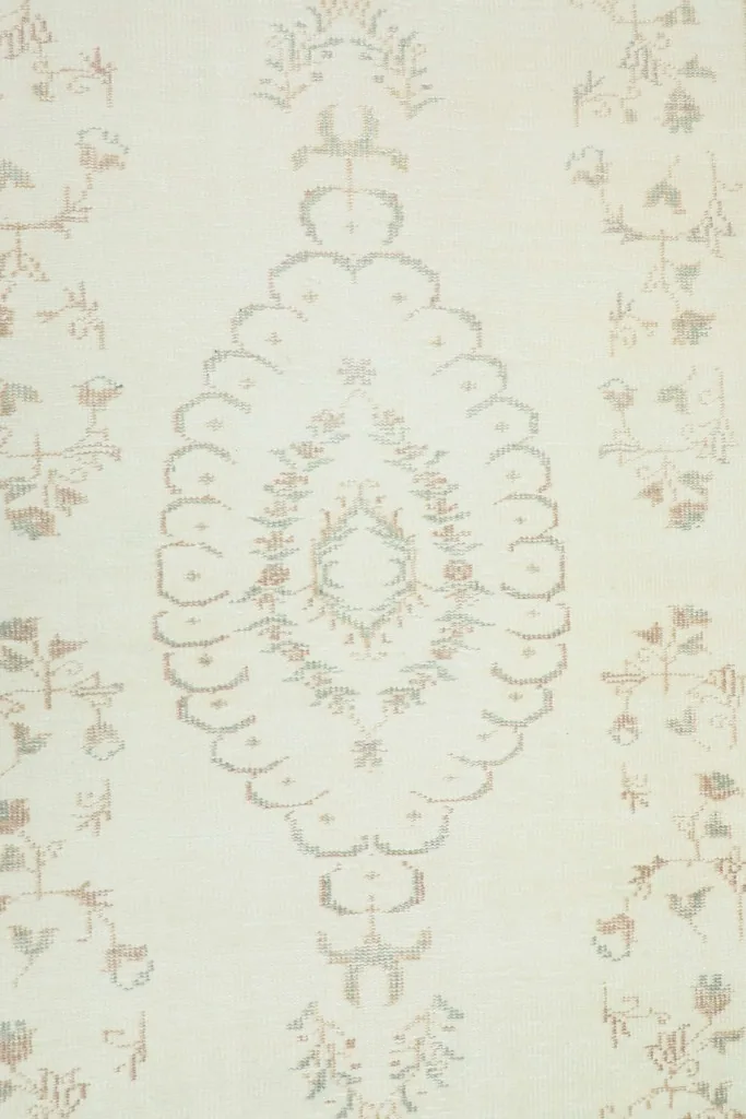 Overhead view of the central medallion design on the ivory field with subtle floral accents.