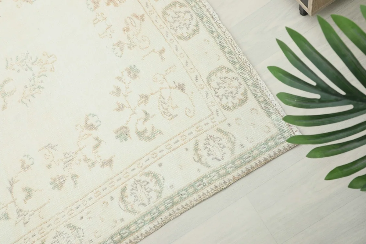 Close-up of the rug's border design featuring beige and olive patterns on the ivory background.