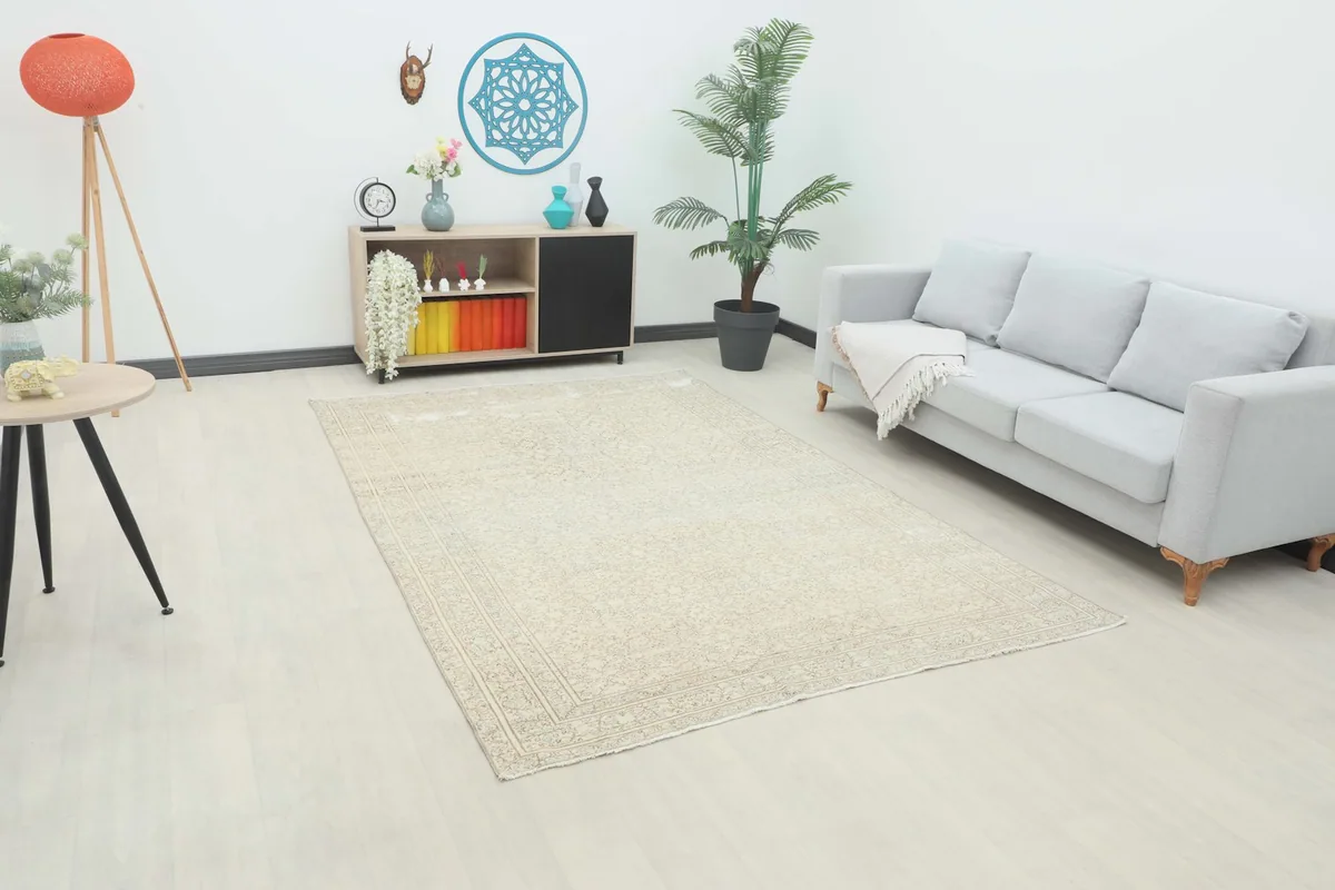 Beige floral vintage Anatolian rug in a living room setting with a light gray sofa
