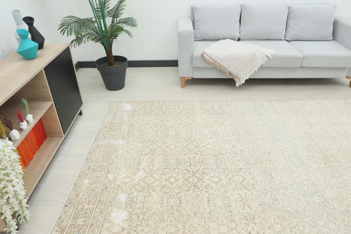 Angle view of the beige floral rug placed in a bright room, showing its scale next to furniture